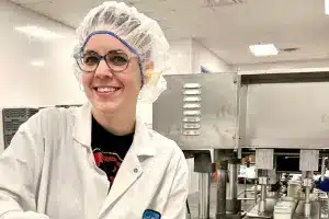 Production worker standing proudly in front of bottling machine